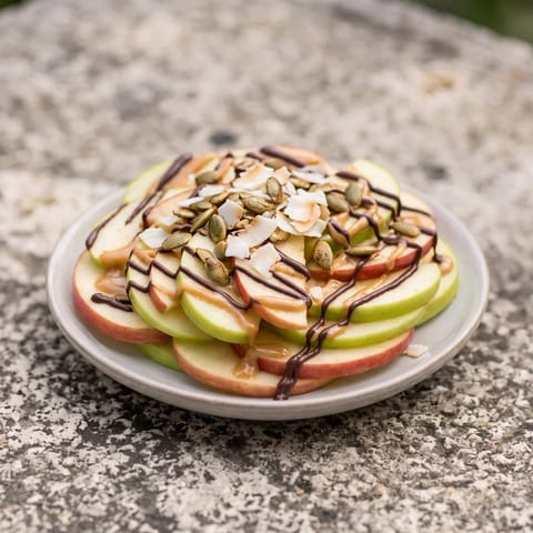Apple Nachos with Peanut Butter Drizzle - Crisp apple slices fanned out under warm peanut butter, dark chocolate and toasted seeds