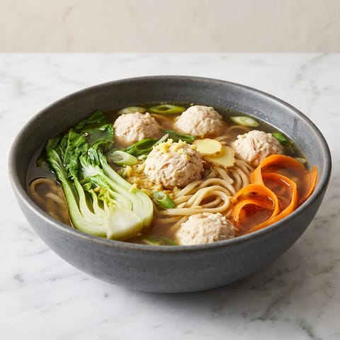 Chicken & Vegetable Dumpling-Style Noodle Soup - Ginger-poached chicken and wontons' spirit without the wrapping: plump chicken meatballs in a scallion broth with noodles and greens.