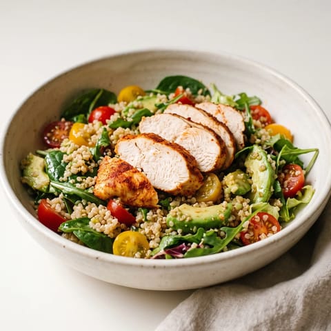 Chicken, Avocado & Quinoa Bowl - Paprika-rubbed chicken sliced over quinoa with avocado, tomatoes and leaves in a lime dressing