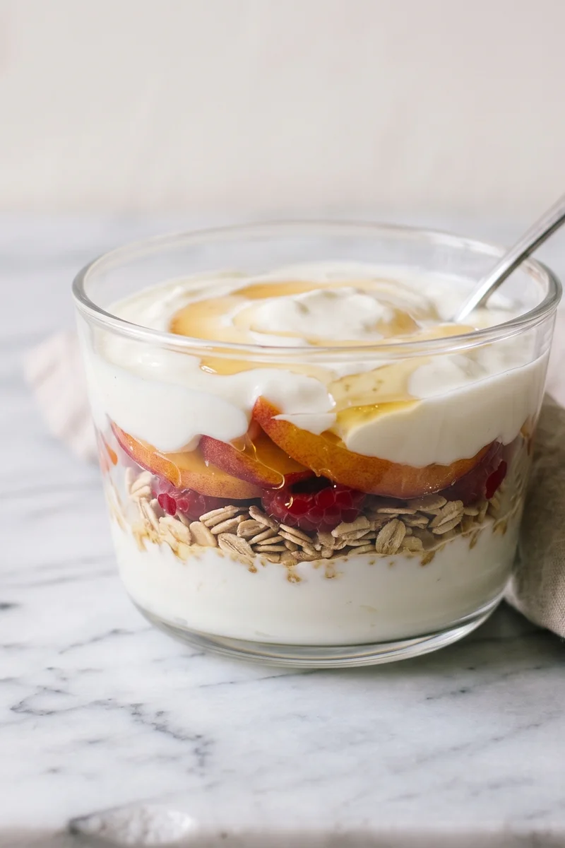 Peach Melba Yogurt Parfait - Layers of thick yogurt, warm honeyed peaches and raspberry smash with toasted oats